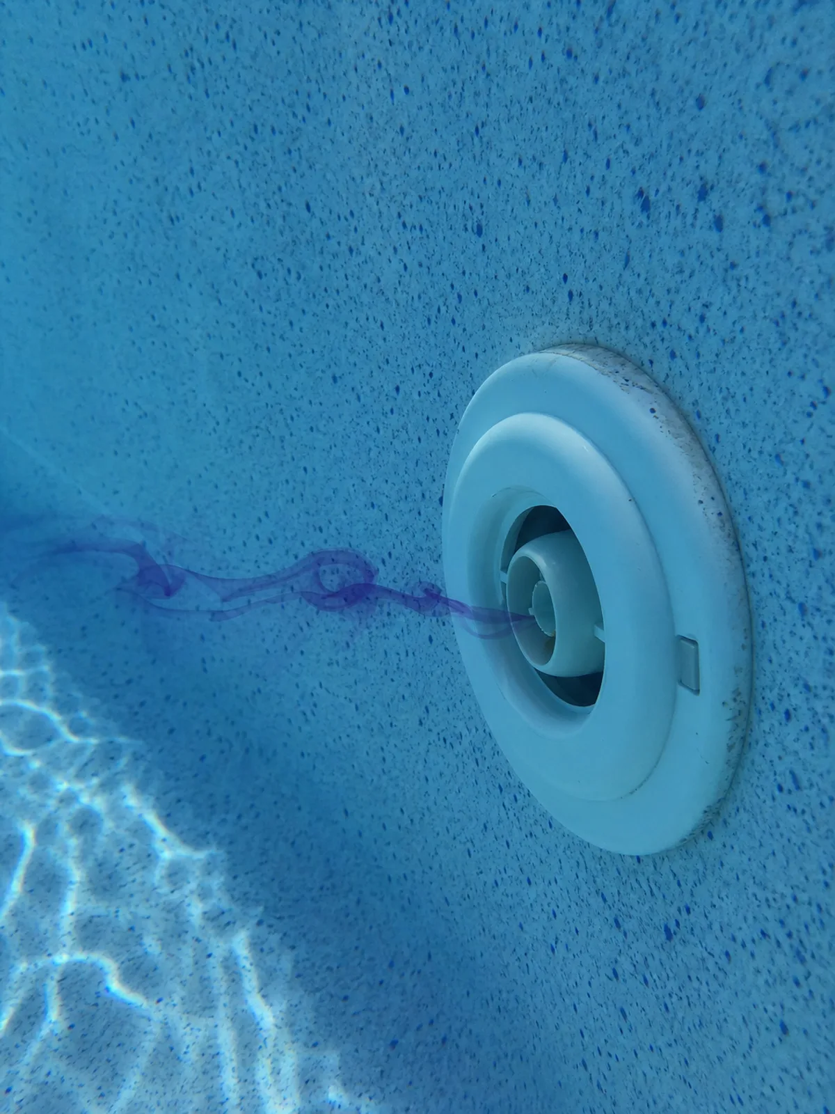 Dye test at a pool return fitting, showing test dye drawn toward a suspected leak