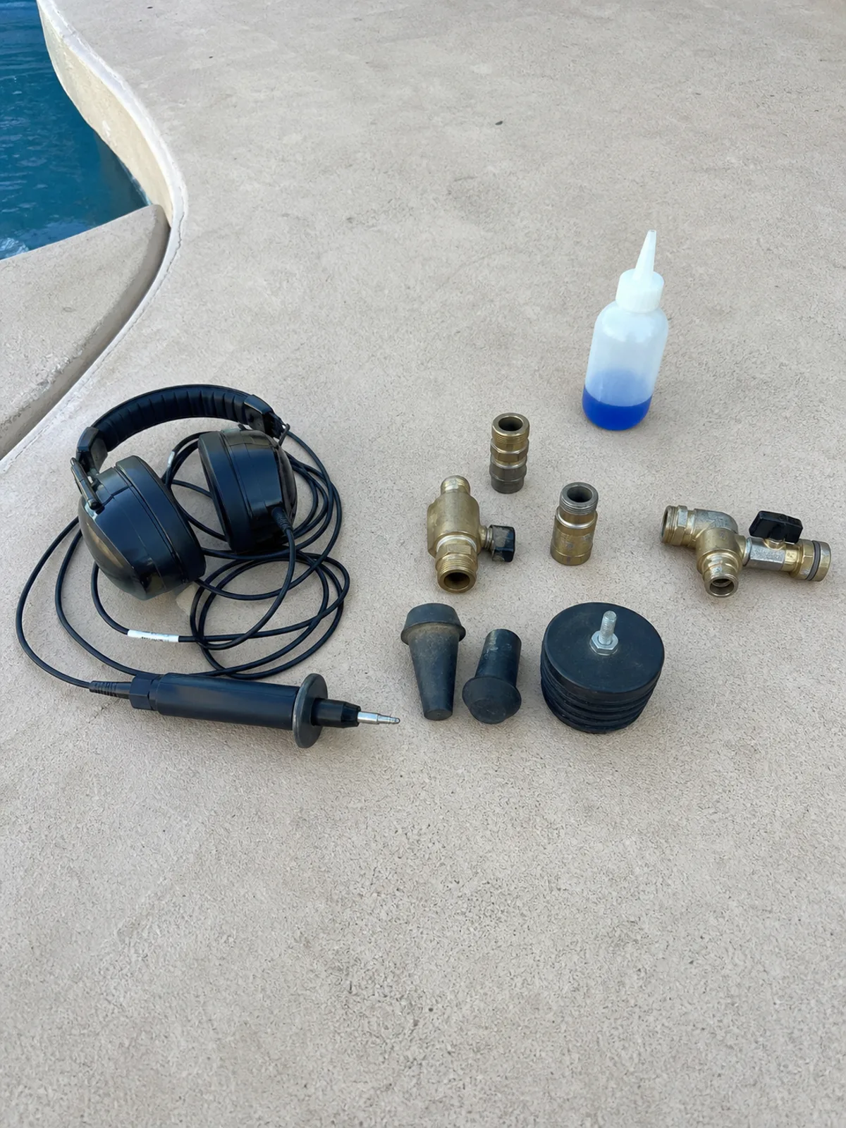 Electronic listening probe, dye-test bottle, and pressure-test fittings used to locate pool leaks